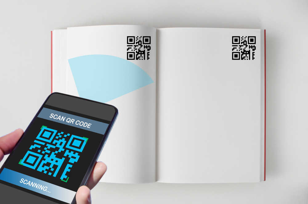 Na imagem, há um celular que aponta para o livro, lendo um QR Code que está disponível nas páginas, simbolizando a temática do contéudo digital no material didático.
