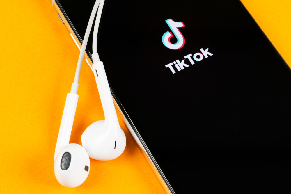 A imagem traz a foto de um celular, onde na tela tem o aplicativo TikTok. A imagem é usada para ilustrar a influência do TikTok na educação através da microaprendizagem.